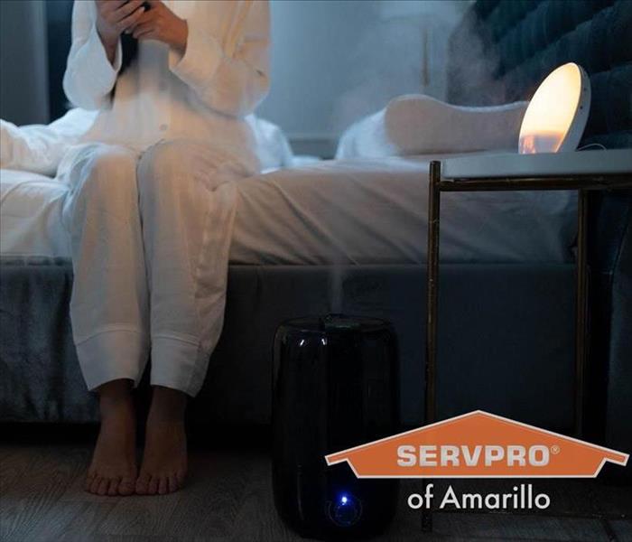 Humidifier in home, and woman sitting at the edge of her bed